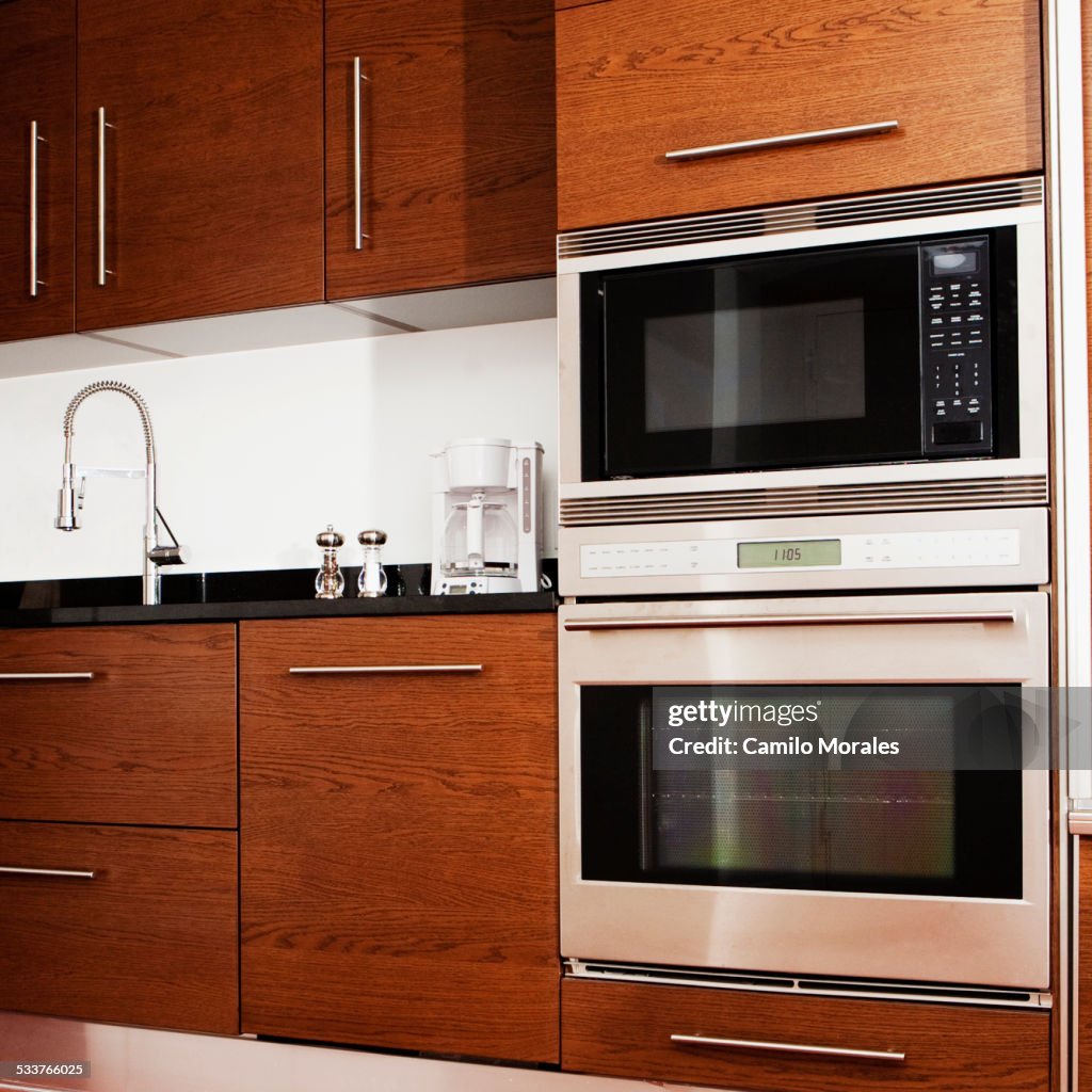 Oven, microwave, cabinets and sink in modern kitchen