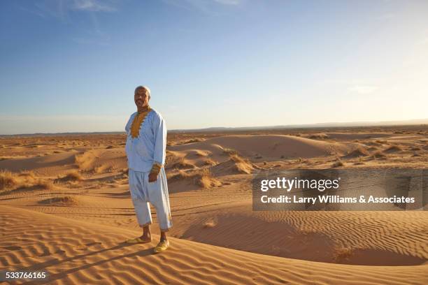 guide smiling on sand dunes in desert landscape - 民族衣装 ストックフォトと画像