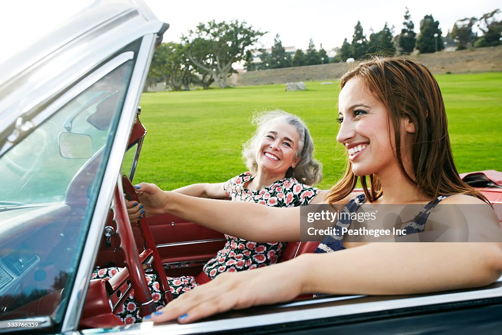 Mother and daughter driving in classic convertible