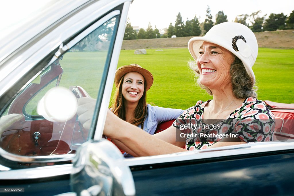 Mother and daughter driving in classic convertible