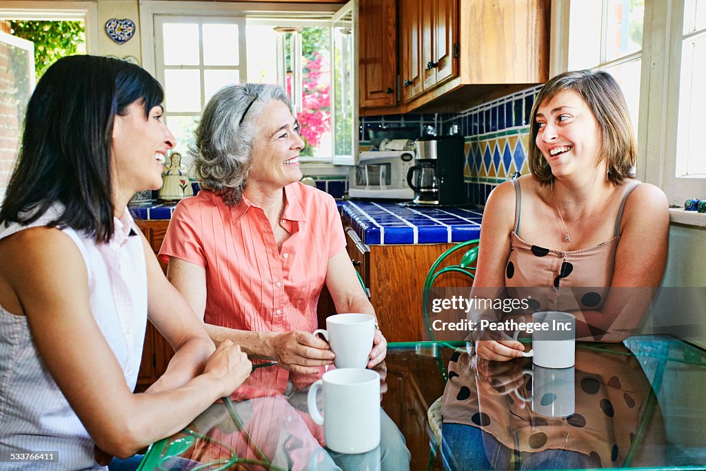 Caucasian mother and daughters drinking coffee in kitchen
