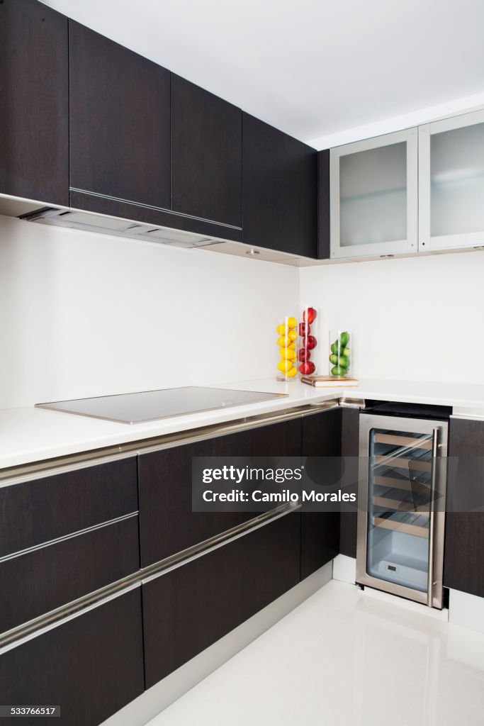 Cabinets, stove and miniature refrigerator in modern kitchen