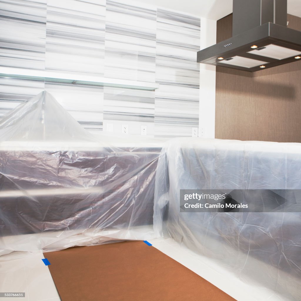 Tarps covering surfaces in modern kitchen under renovation