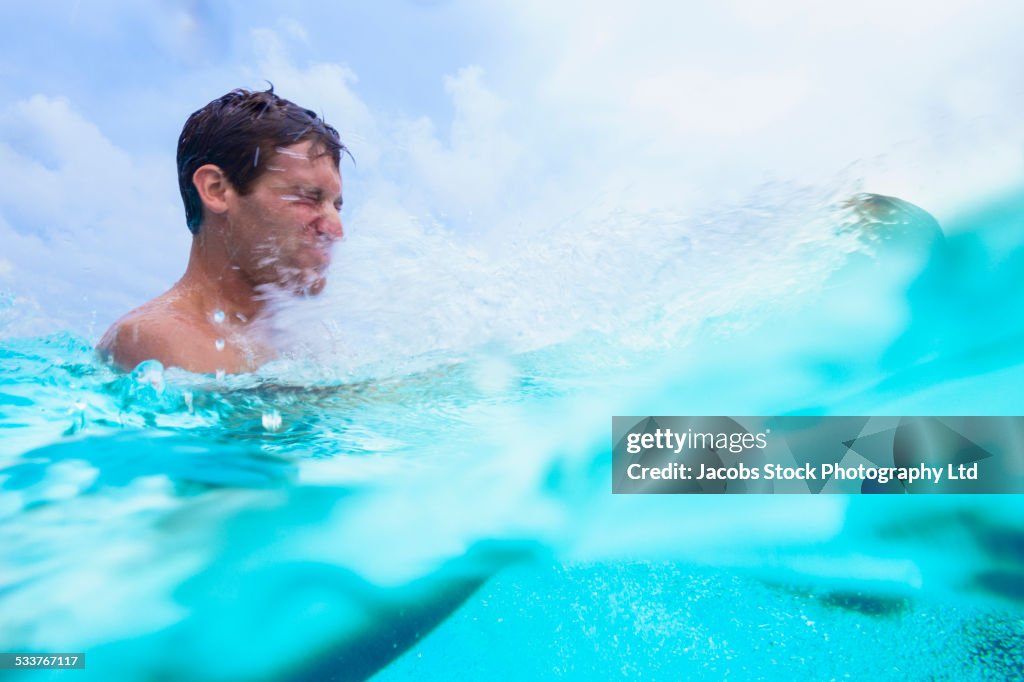 Caucasian couple splashing in swimming pool