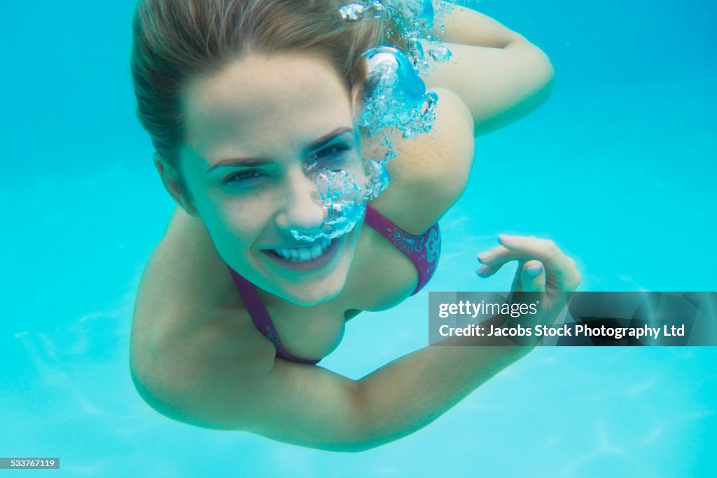 Caucasian woman swimming underwater in pool