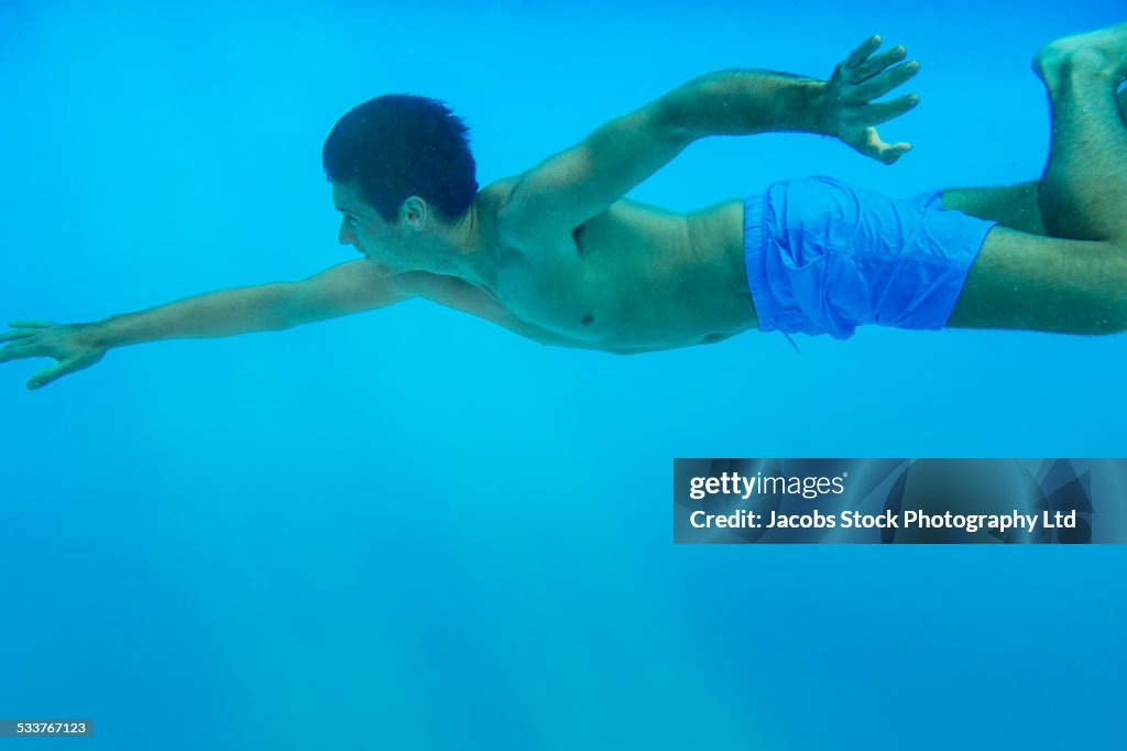 Caucasian man swimming underwater in pool