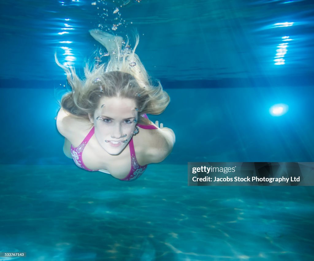Caucasian woman swimming underwater in pool