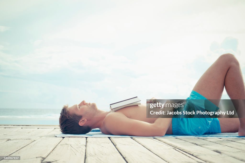 Caucasian man sunbathing on wooden dock