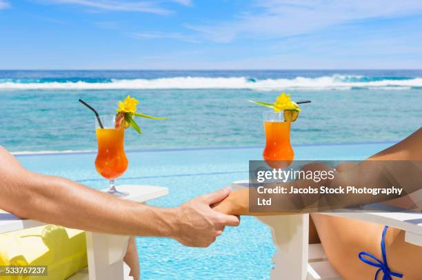 caucasian couple relaxing in adirondack chairs near swimming pool - cook islands stock pictures, royalty-free photos & images