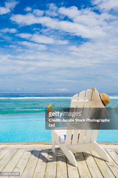 adirondack chair with juice, sun hat and sunglasses near swimming pool - adirondack chair stockfoto's en -beelden
