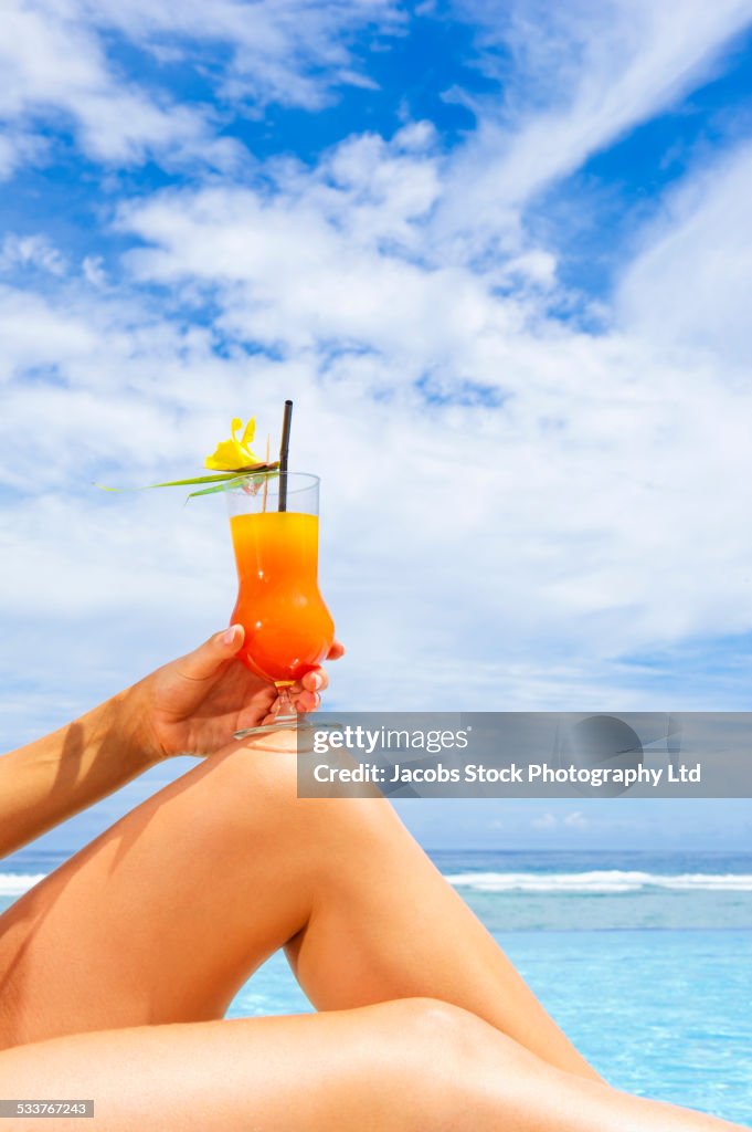 Caucasian woman drinking cocktail at beach