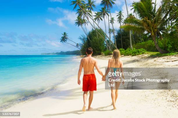 caucasian couple holding hands on tropical beach - rarotonga fotografías e imágenes de stock