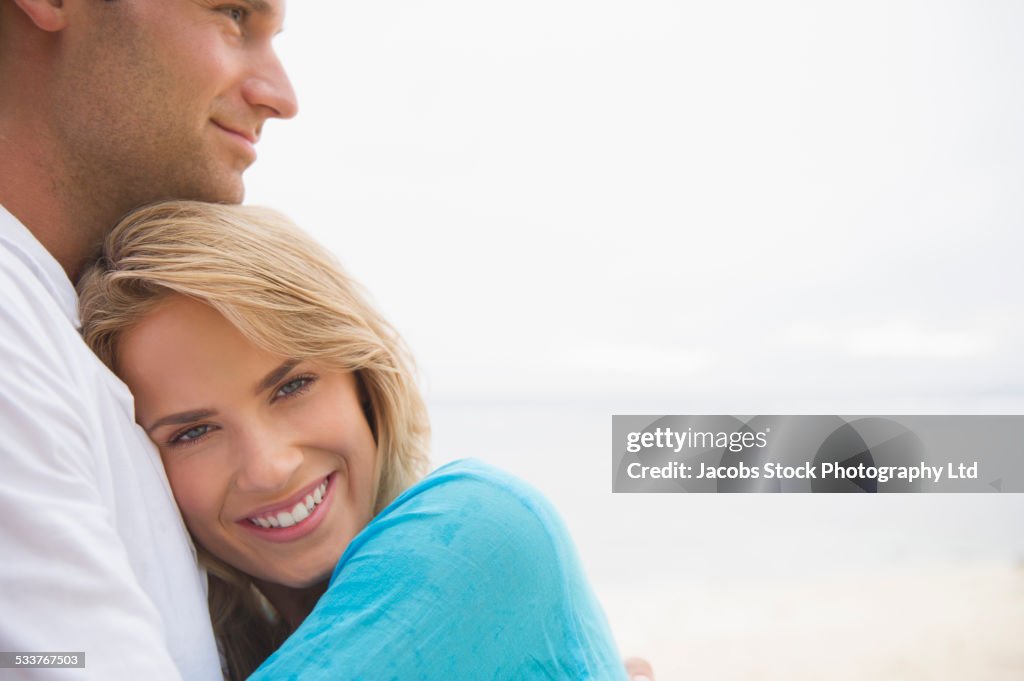 Caucasian couple hugging at beach