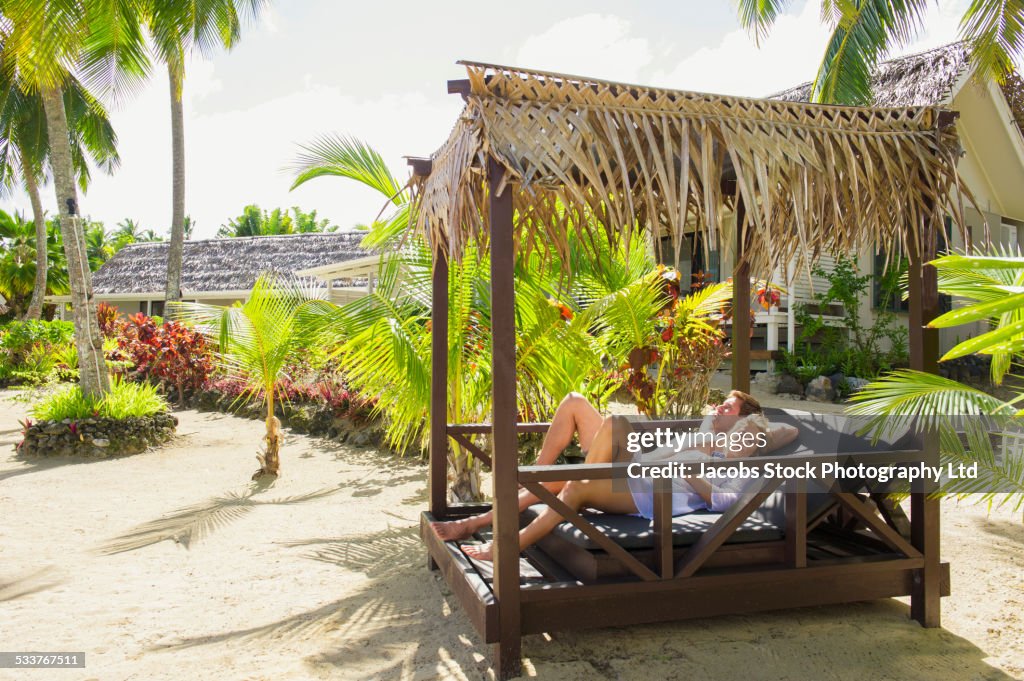 Caucasian couple relaxing in cabana on tropical beach