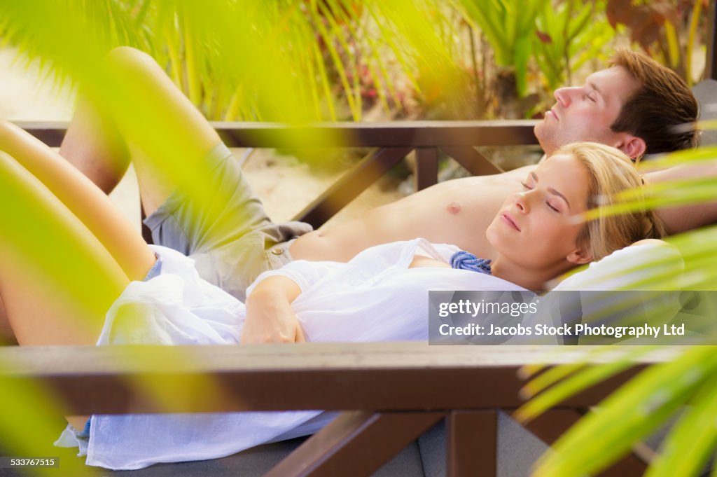 Caucasian couple napping in cabana on tropical beach