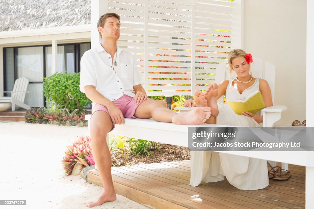 Caucasian couple relaxing on porch railing