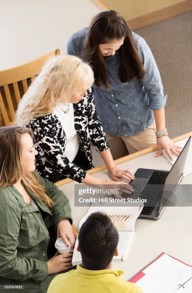 Teacher and students using laptop in meeting