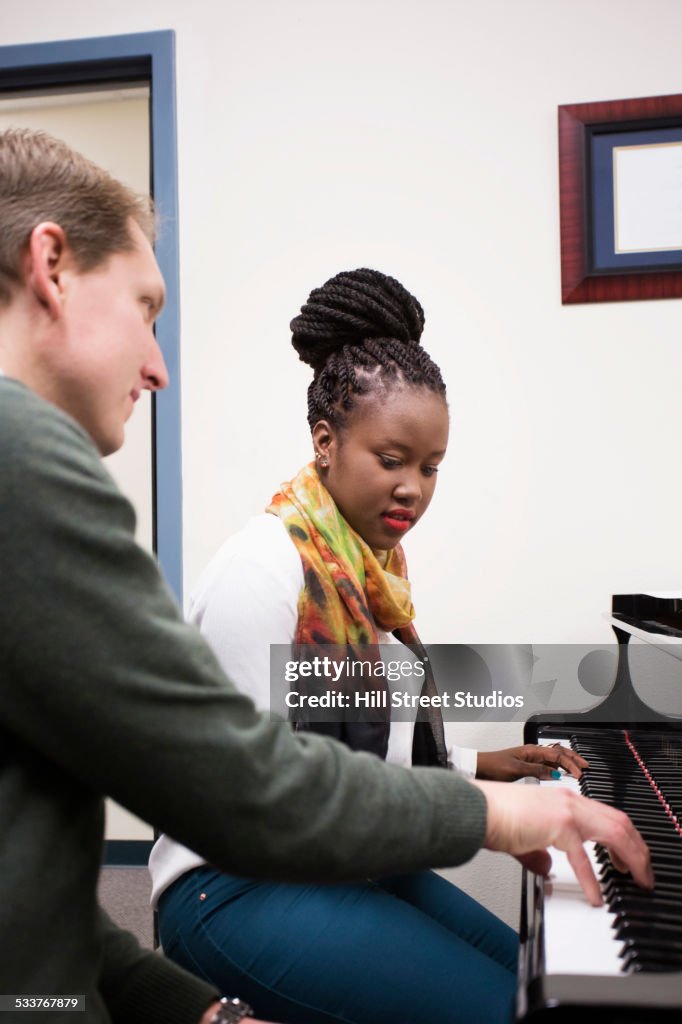 Music teacher and student practicing at piano