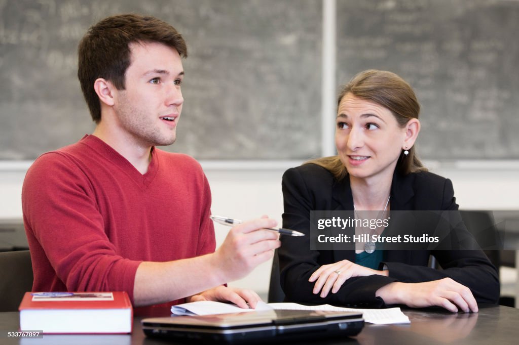 Caucasian student and teacher talking in classroom