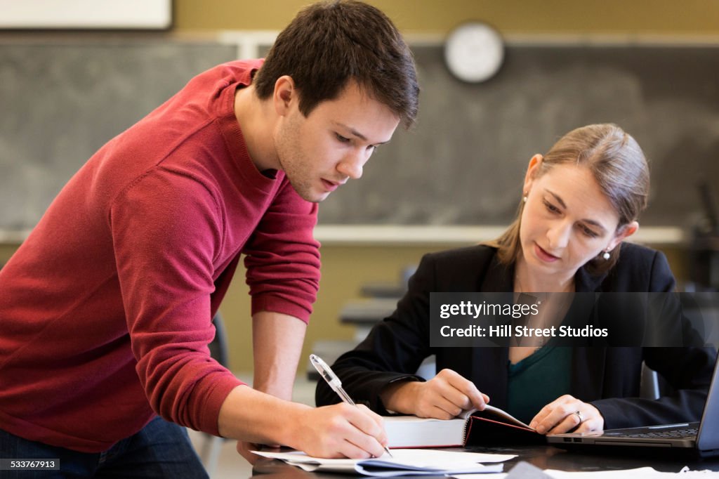 Caucasian student and teacher studying in classroom