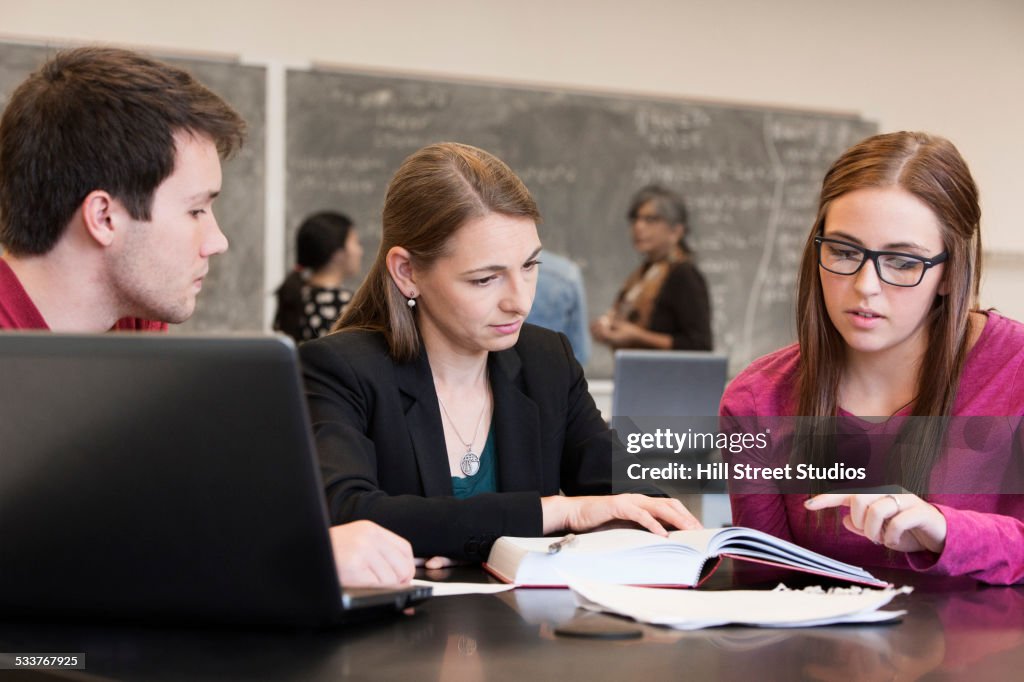 Caucasian students and teacher studying in classroom