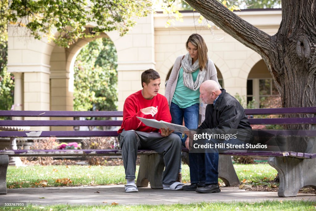 Students and teacher talking on park benches