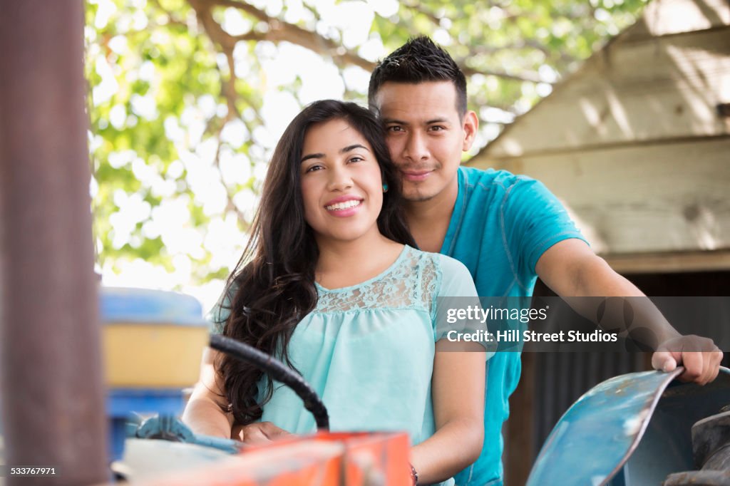 Hispanic couple riding tractor on ranch