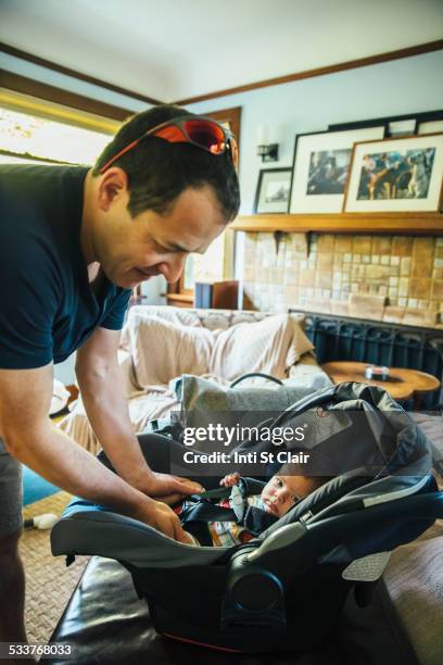 caucasian father fastening baby boy in car seat - safe kids day arrivals stock pictures, royalty-free photos & images