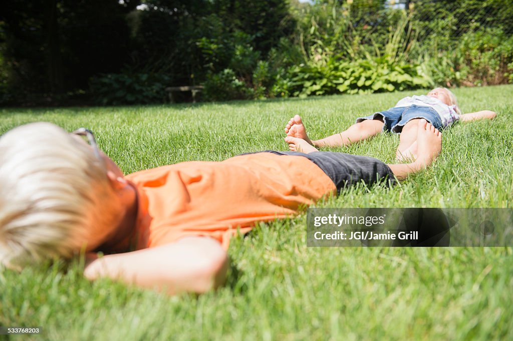 Caucasian children laying on lawn in backyard