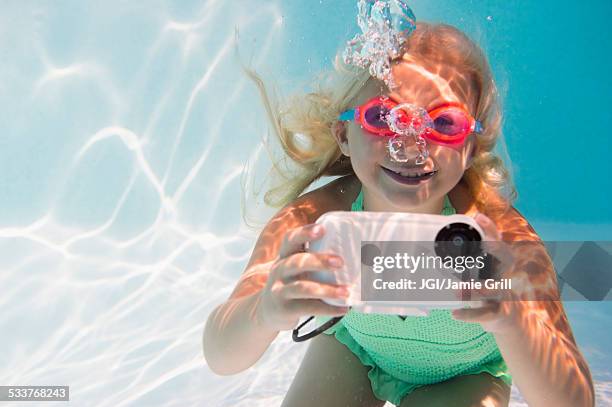 caucasian girl taking photograph underwater in pool - macchina fotografica subacquea foto e immagini stock