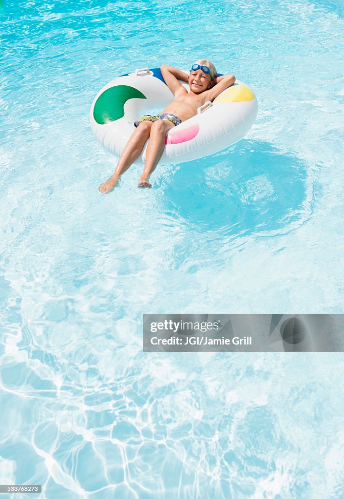 Caucasian boy floating in inflatable ring in swimming pool