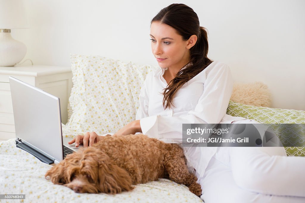 Caucasian woman using laptop with pet dog