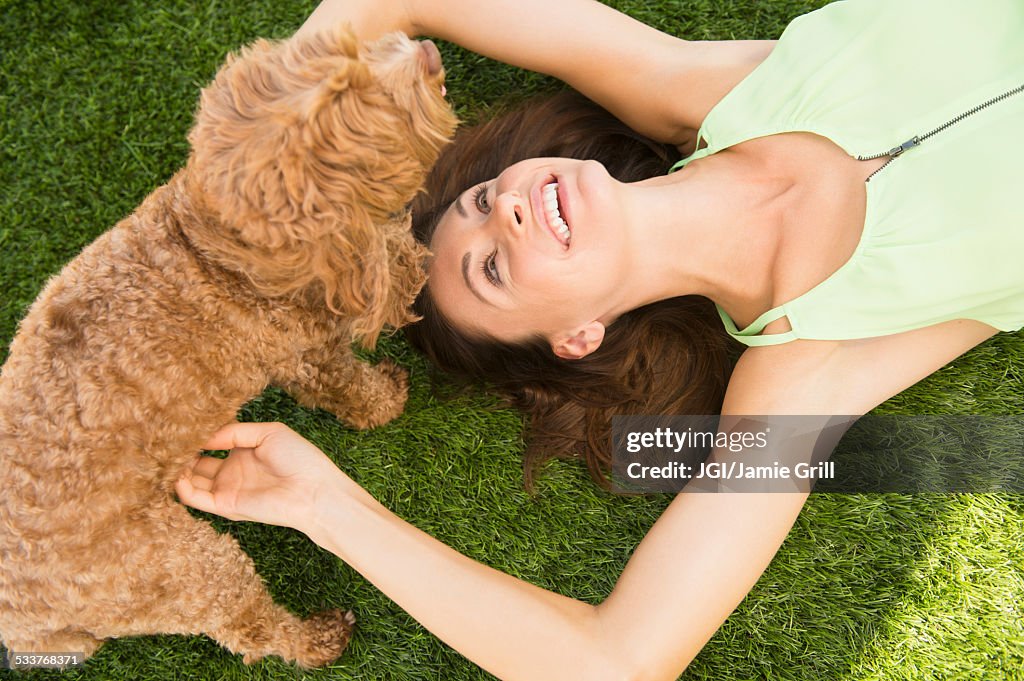 Caucasian woman playing with dog on lawn