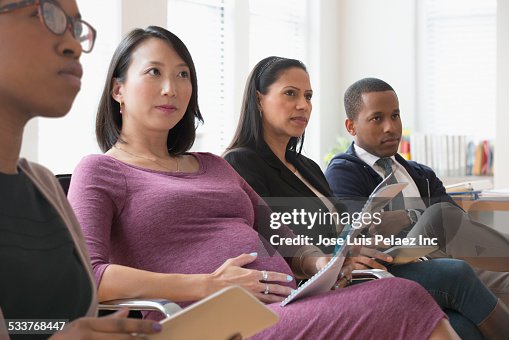 Business people listening in presentation in office Business people listening in presentation in office