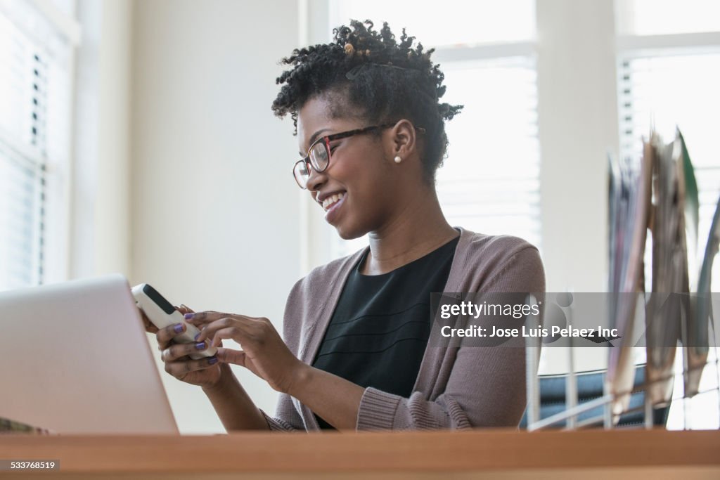 Black businesswoman using cell phone in office
