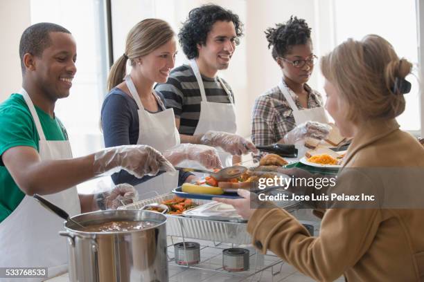 volunteers serving food in cafeteria - femme bras tendu cuillère photos et images de collection