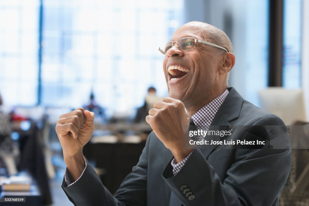 Black businessman cheering in office