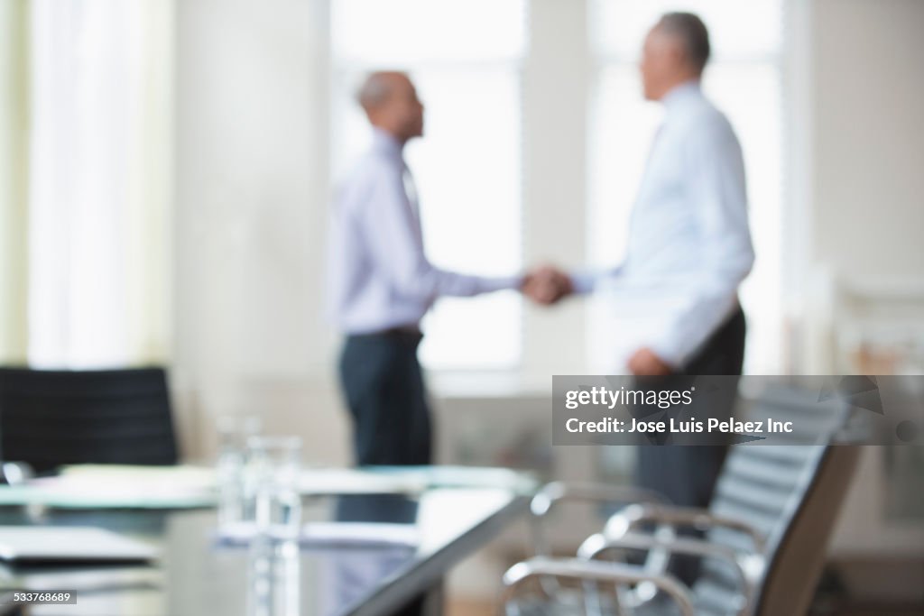 Businessmen shaking hands office meeting