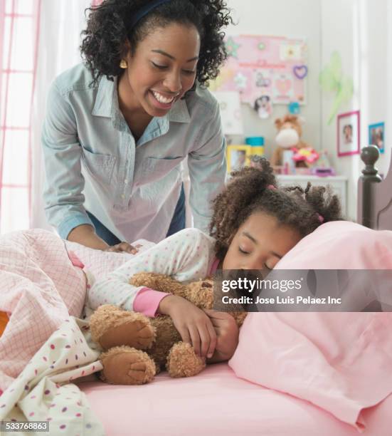 mother tucking daughter into bed - tuck in bed stock pictures, royalty-free photos & images