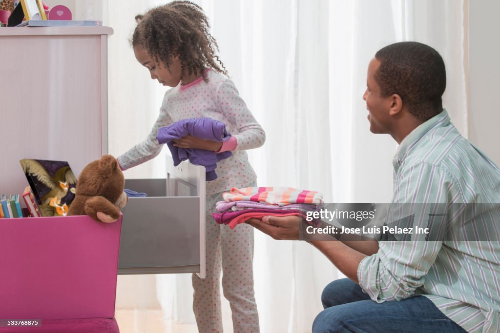 Father and daughter placing laundry in drawers