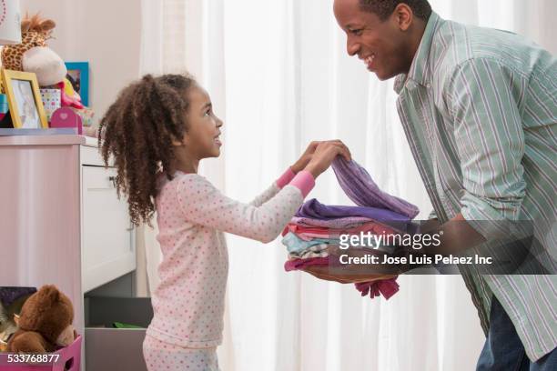 father and daughter placing laundry in drawers - afazeres domésticos - fotografias e filmes do acervo