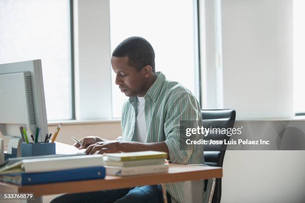 mixed race businessman working at desk - adult learning stock pictures, royalty-free photos & images