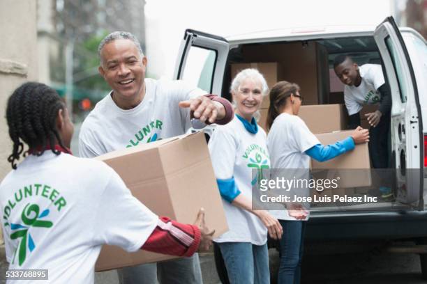 volunteers passing cardboard boxes from delivery van - ボランティア ストックフォトと画像