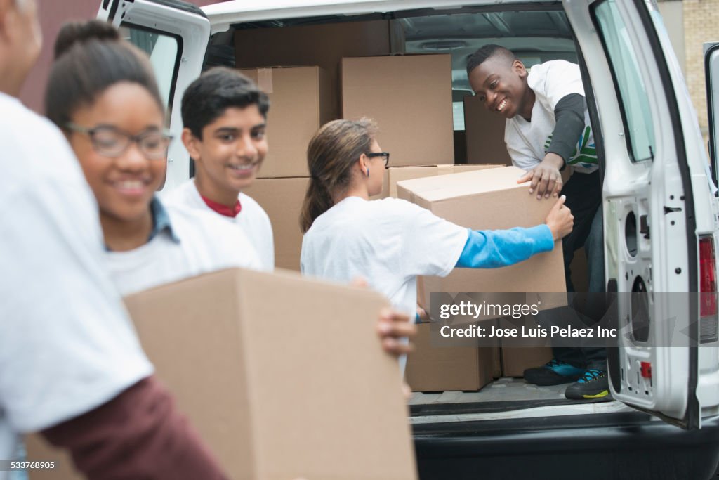 Volunteers passing cardboard boxes from delivery van