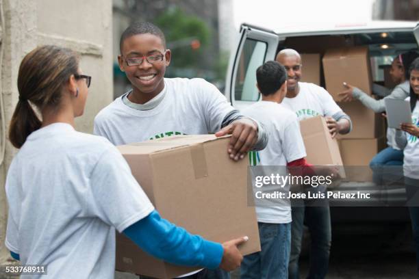 volunteers passing cardboard boxes from delivery van - boy gift stockfoto's en -beelden