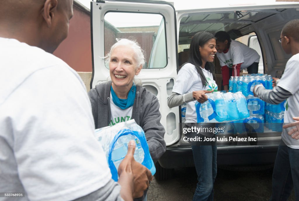 Volunteers passing stacks of bottled water from delivery van