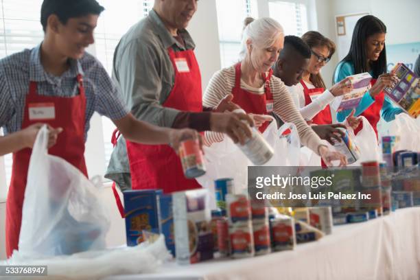 volunteers packing canned goods at food drive - charity and relief work stock pictures, royalty-free photos & images