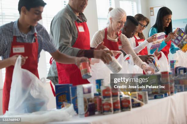 volunteers packing canned goods at food drive - recolha-de-alimentos imagens e fotografias de stock