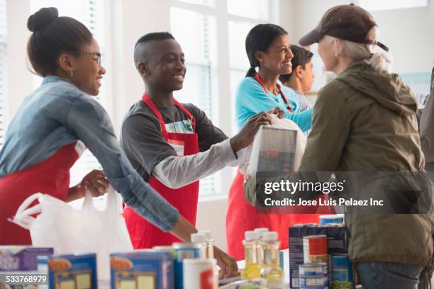 volunteers handing out food at food drive - boy gift stockfoto's en -beelden