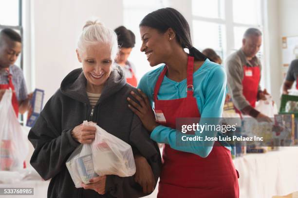 volunteer handing out food at food drive - liefdadigheidsinstelling stockfoto's en -beelden